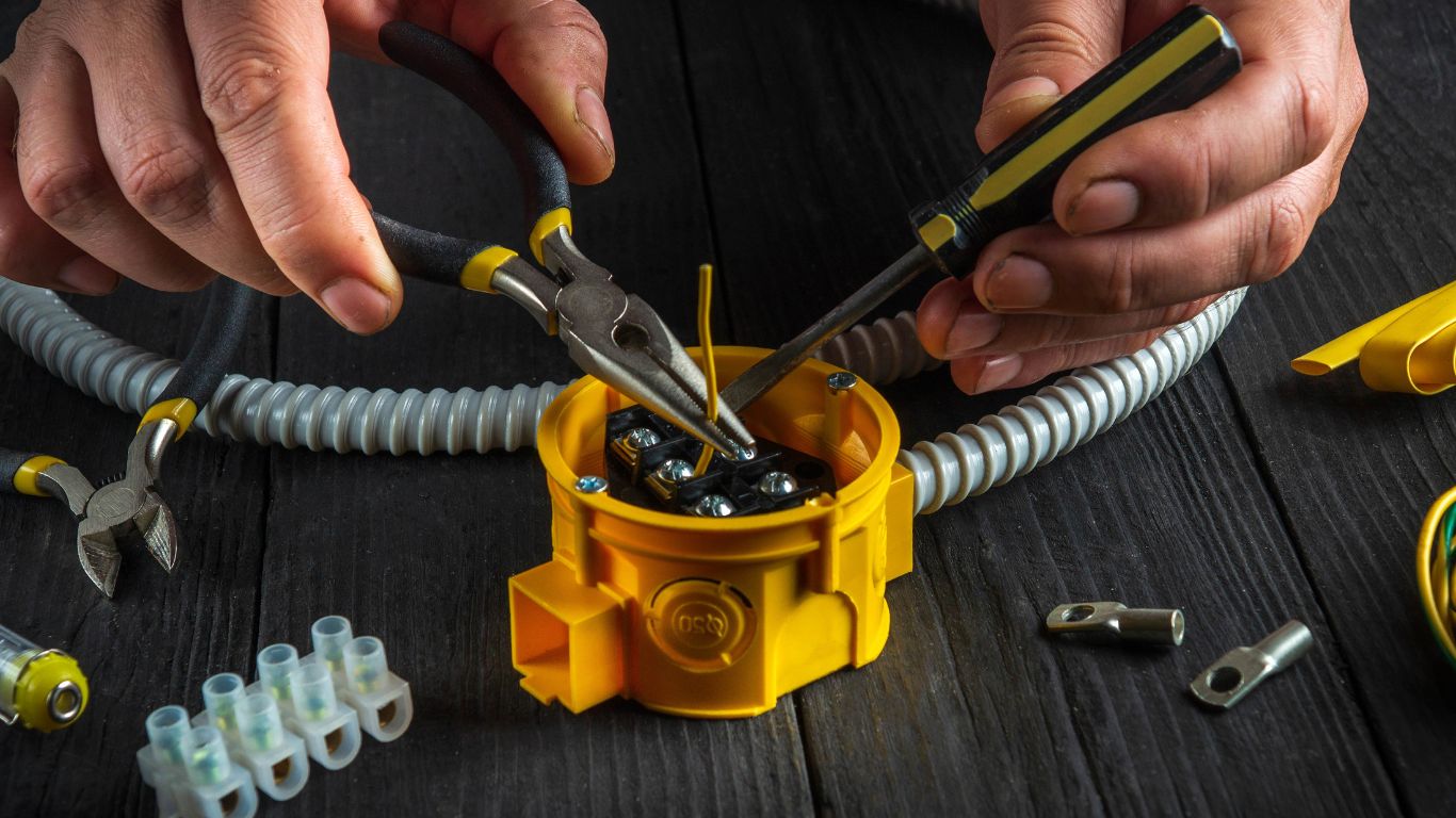 An electrician installing cable wires at the junction box.